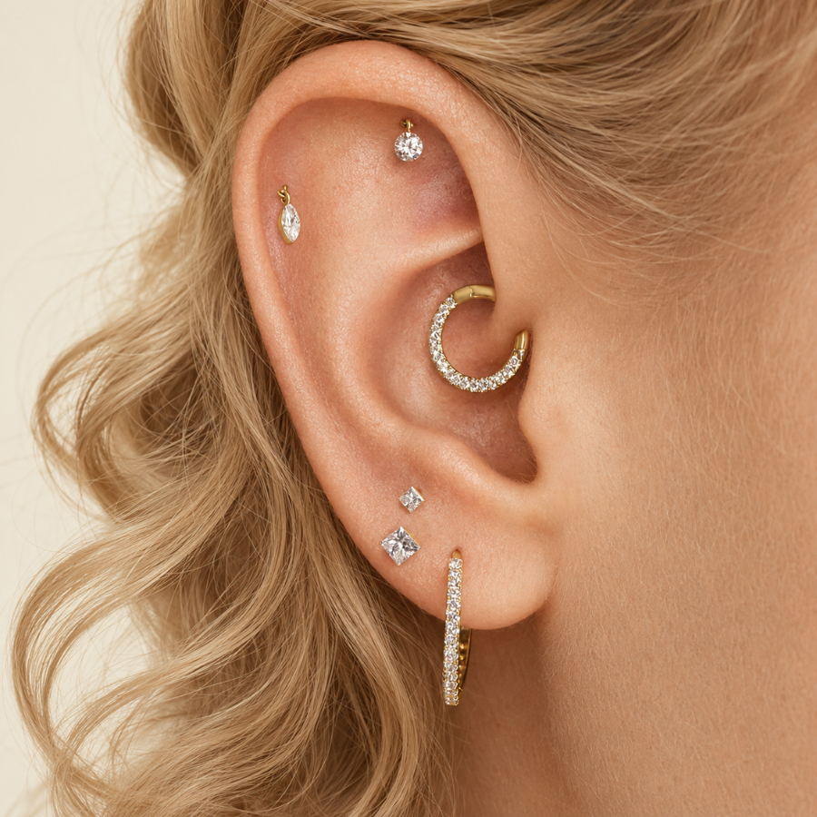DOVIANA 14K solid gold diamond drop threaded flat back earring styled in a curated ear stack on a model with curly blonde hair.