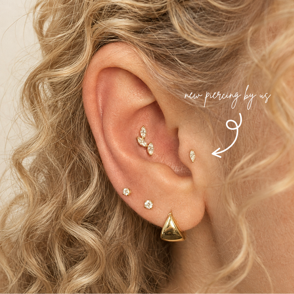 DOVIANA 14K solid gold oval CZ threadless labret flat back earring styled in a curated ear stack on a model with curly blonde hair.