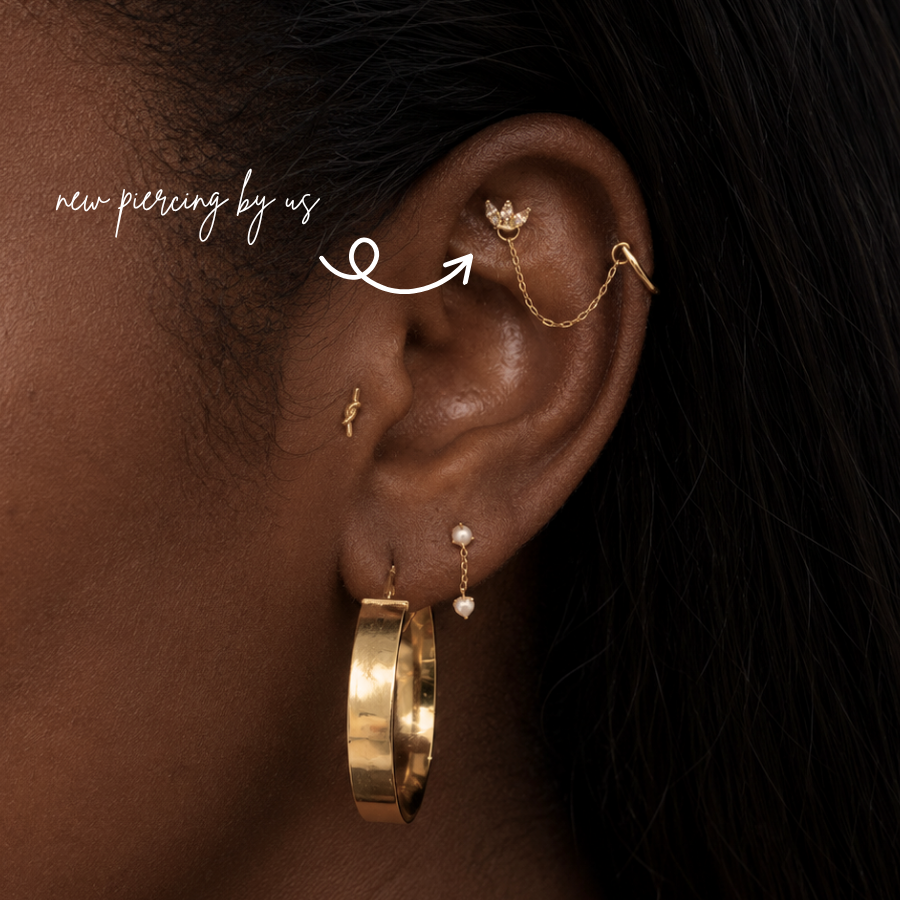 DOVIANA NYC curated ear piercing featuring a 14K solid gold stud connector chain on a helix style trefoil stud piercing, styled with gold hoops, pearl dangle jewelry, and minimalist fine piercing jewelry in New York.