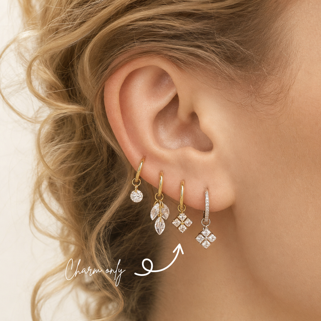 DOVIANA four-stone princess-cut CZ ear charm in PVD gold titanium, styled on a hoop in a curated ear stack. Charm sold individually; hoop not included.