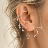 DOVIANA pear-cut CZ cross ear charm made from silver-tone titanium, styled on a pavé hoop earring. Charm sold individually; hoop not included.