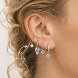 Close-up of a blonde woman wearing a DOVIANA round CZ titanium ear charm on a silver hoop with coordinating dangle charms. Charm sold separately; hoop not included.