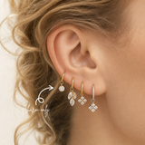 Close-up of a blonde woman wearing a DOVIANA round cubic zirconia ear charm in PVD gold titanium on a hoop. Charm sold separately; hoop not included.