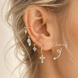 DOVIANA pear-cut CZ cross ear charm in PVD gold titanium, styled on a hoop earring.