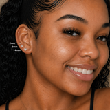 Close-up of a woman wearing DOVIANA 14k solid gold diamond stud earrings in 2mm, 3mm, and 4mm sizes, styled in a curated ear stack with natural glowing skin, visible texture and freckles, and soft diffused lighting for an editorial jewelry look.