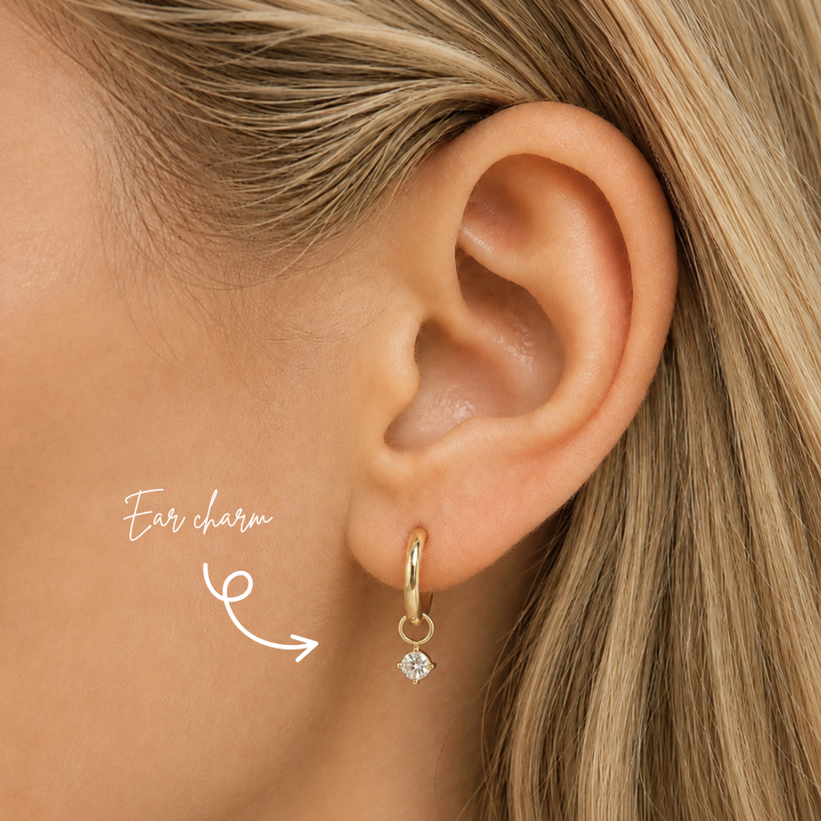 Blonde woman wearing a DOVIANA 14K solid gold round lab-grown diamond ear charm in a four-prong setting on a hoop, highlighted by an arrow.