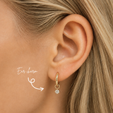 Blonde woman wearing a DOVIANA 14K solid gold round lab-grown diamond ear charm in a four-prong setting on a hoop, highlighted by an arrow.