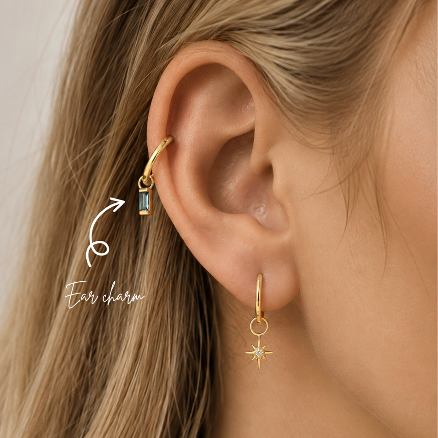 Blonde woman wearing a DOVIANA 14K solid gold baguette blue topaz ear charm on a helix hoop, highlighted by an arrow.