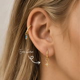 Blonde woman wearing a DOVIANA 14K solid gold North Star lab-grown diamond ear charm on a lobe hoop, highlighted by an arrow.