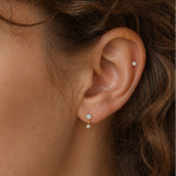 14K gold opal dangle flat back earring on a real human ear with soft curly hair, featuring a small diamond stud helix piercing, natural skin texture and minimal luxury jewelry styling by DOVIANA NYC