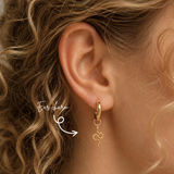 Blonde woman wearing a DOVIANA 14K solid gold textured snake ear charm with a sculptural serpent design on a hoop, highlighted by an arrow.