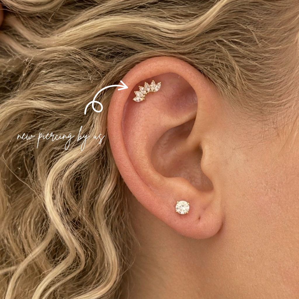 White woman with curly blonde hair wearing DOVIANA 14K solid gold marquise cluster CZ crawler threadless labret flat back earring on ear, featuring delicate marquise-cut cubic zirconia stones in a curved crawler design with natural skin texture visible