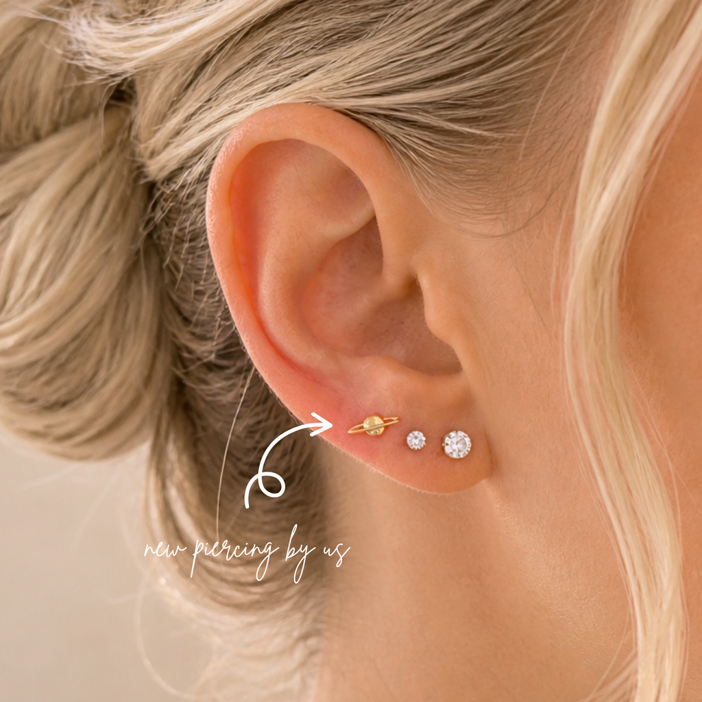 Close-up of ear wearing DOVIANA 14K solid gold planet celestial body threadless labret flat back earring, styled with diamond studs for a dainty cartilage piercing and minimal everyday ear stack.