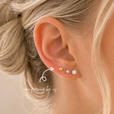 Close-up of ear wearing DOVIANA 14K solid gold planet celestial body threadless labret flat back earring, styled with diamond studs for a dainty cartilage piercing and minimal everyday ear stack.