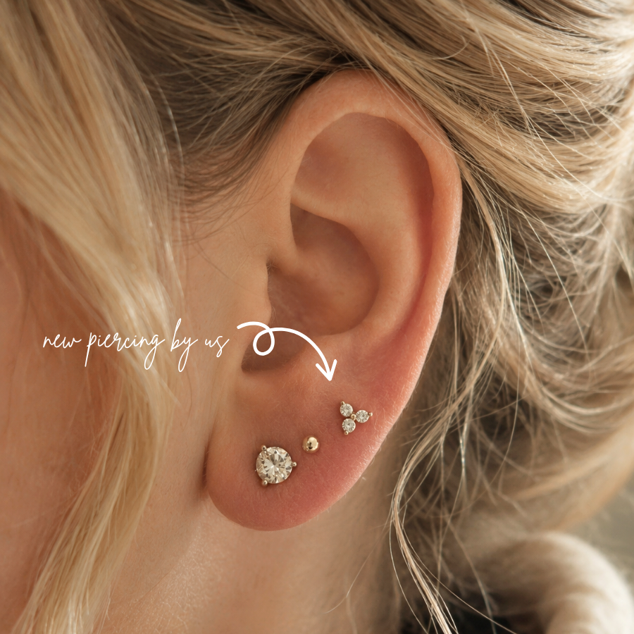Close-up of 14K solid gold Trefoil CZ threadless flat back earring styled in a curated ear stack with minimalist lobe piercings at DOVIANA NYC.