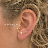 White woman with curly blonde hair wearing DOVIANA 14K solid gold triple CZ barnacle trio curved bar threadless labret flat back earring on lobe, featuring three dainty cubic zirconia stones in a curved design with natural skin texture visible