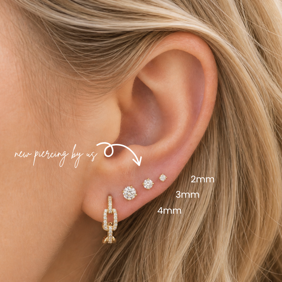 Close-up of 2mm, 3mm, and 4mm 14K solid gold CZ flat back earrings styled in a minimalist lobe piercing stack with diamond studs at DOVIANA NYC.