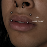 Close-up of angel fangs lip piercings with black spike jewelry and septum piercing styled in alternative body jewelry aesthetic at DOVIANA NYC.
