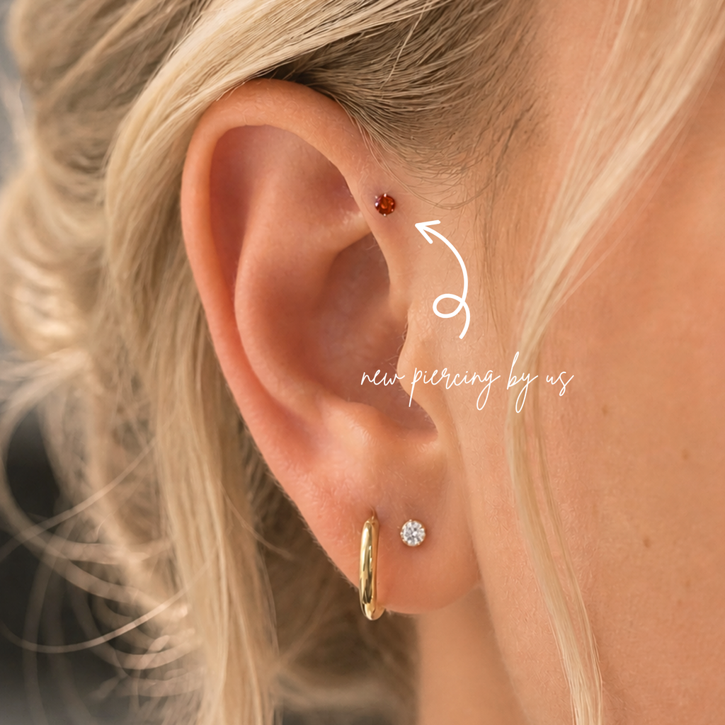 Close-up of ear wearing DOVIANA classic ruby CZ 2mm threadless labret titanium flat back earring, showcasing dainty red cartilage jewelry for sensitive ears and everyday piercing styling.