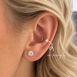 Close-up of a blonde woman’s ear featuring a DOVIANA conch piercing with a 14k solid gold curved CZ flat back earring and a diamond stud on the lobe, showcasing professional ear piercing and curated ear styling in NYC.