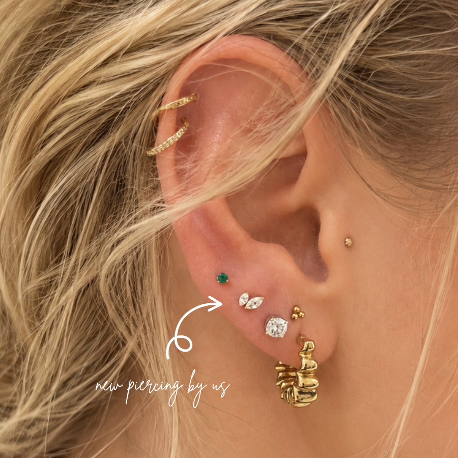 Close-up of curated ear styling with flat and lobe piercings featuring minimalist gold earrings, marquise CZ studs, and cartilage jewelry at DOVIANA NYC.