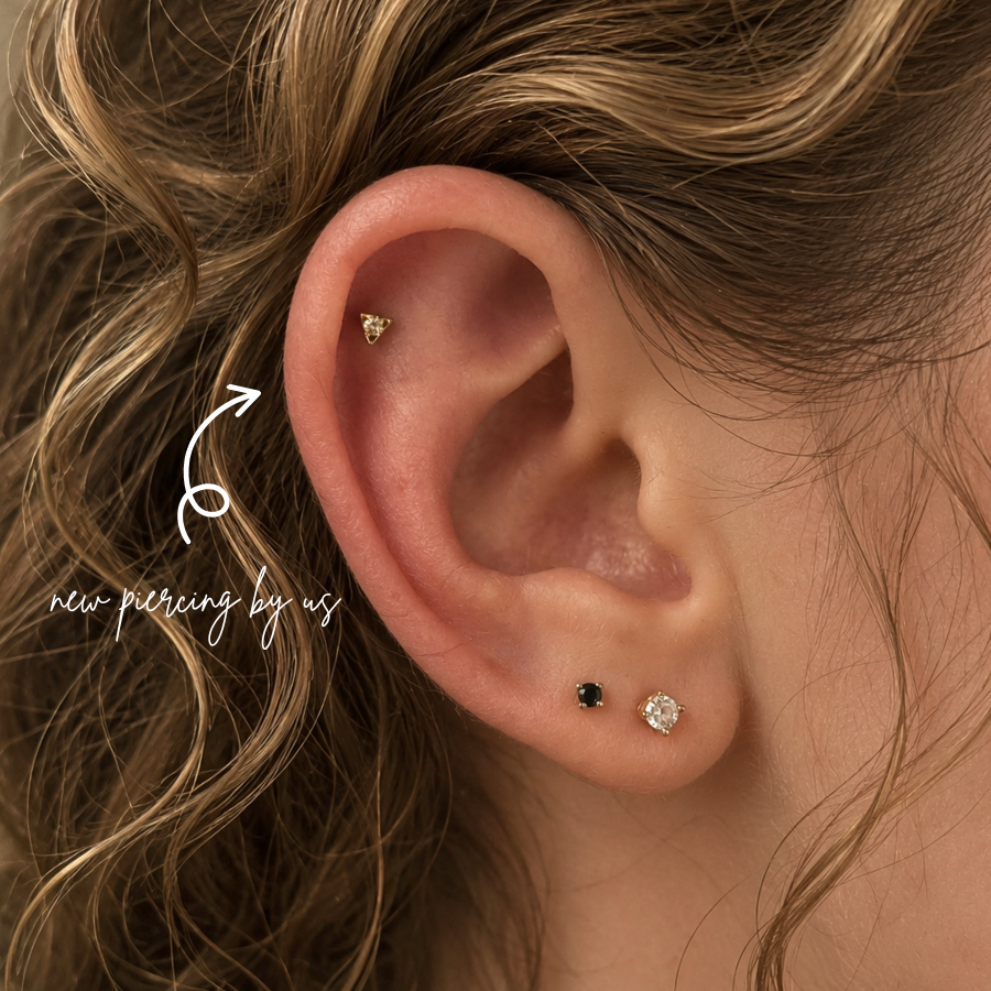Close-up of flat cartilage piercing with gold triangle stud and minimalist lobe earrings styled in a curated ear aesthetic at DOVIANA NYC.