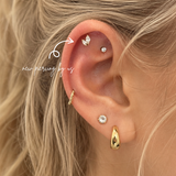 Close-up of curated ear styling featuring Graduated Double Marquise CZ threadless titanium PVD gold flat back earring with helix and lobe piercings at DOVIANA NYC.