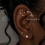 Hidden helix piercing service at DOVIANA featuring 14K solid gold chandelier tassel CZ bezel drop dangle threadless labret flat back earring, luxury cartilage piercing in NYC for sensitive ears