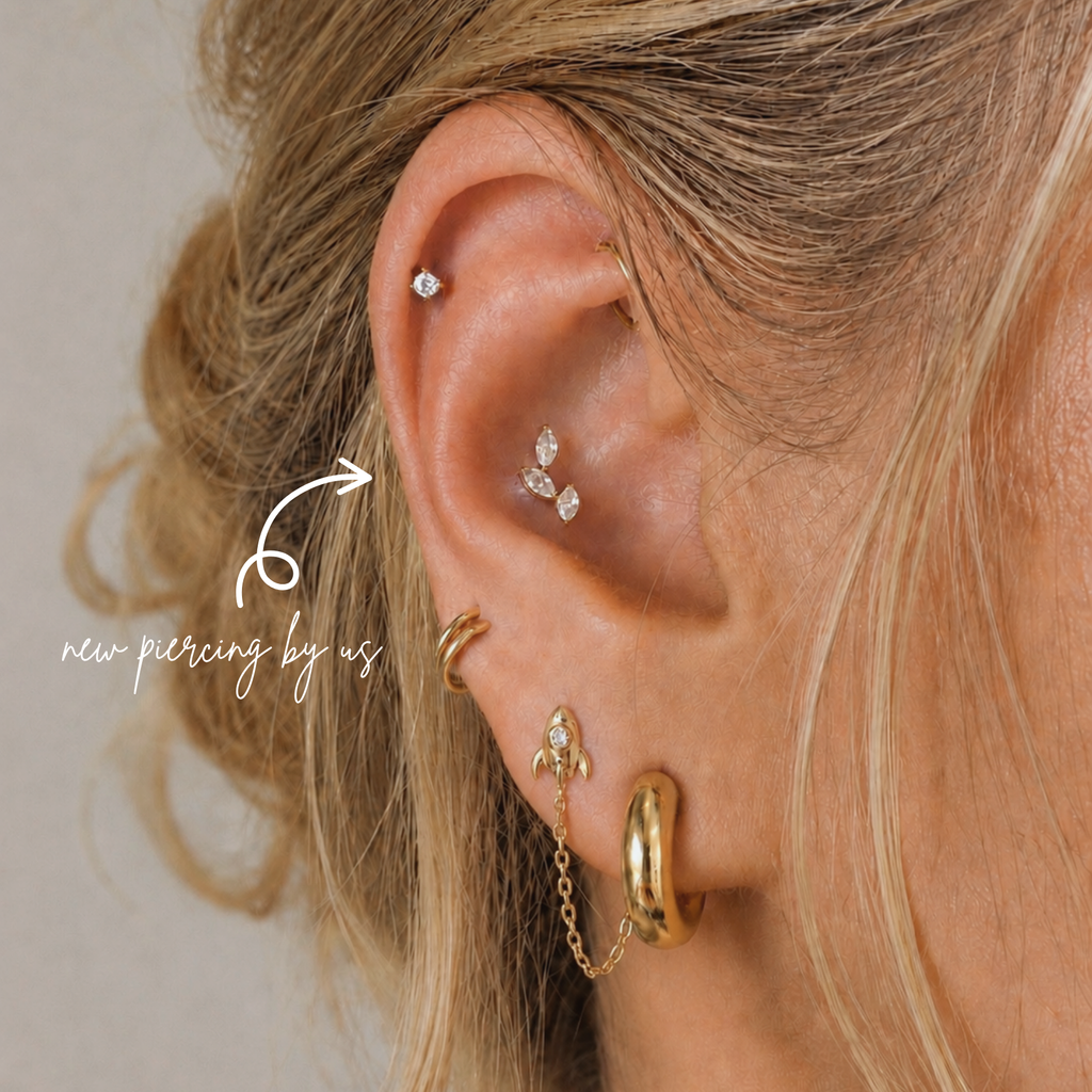 Close-up of curated ear styling featuring Oval CZ Leaves Branch threadless titanium PVD gold flat back earring with helix and lobe piercings at DOVIANA NYC.
