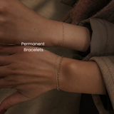 Stacked 14K gold or gold-filled permanent bracelets on wrist at DOVIANA NYC featuring delicate layered chains and gemstone accents for everyday luxury styling