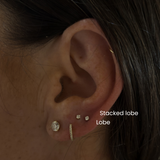 Close-up of ear with DOVIANA stacked lobe piercings featuring gold and diamond earrings, showcasing curated ear styling and professional ear piercing placement in NYC.