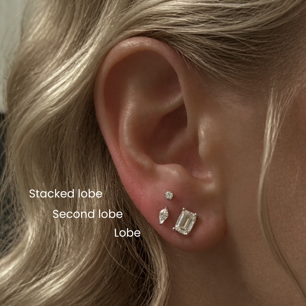 Close-up of a blonde woman’s ear showing DOVIANA stacked lobe and second lobe piercings with dainty diamond stud earrings, illustrating curated ear styling and professional ear piercing placement.