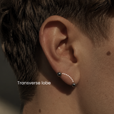 Close-up of a transverse lobe piercing by DOVIANA featuring implant-grade titanium barbell jewelry on a male ear, professionally done with needle piercing in NYC.