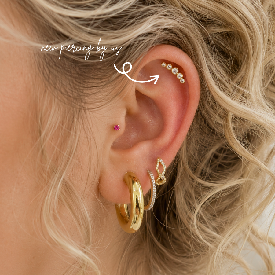 Fresh flat piercing by DOVIANA NYC in Manhattan, New York, featuring a curved gold CZ cluster, professional cartilage piercing services, and personalized ear styling.