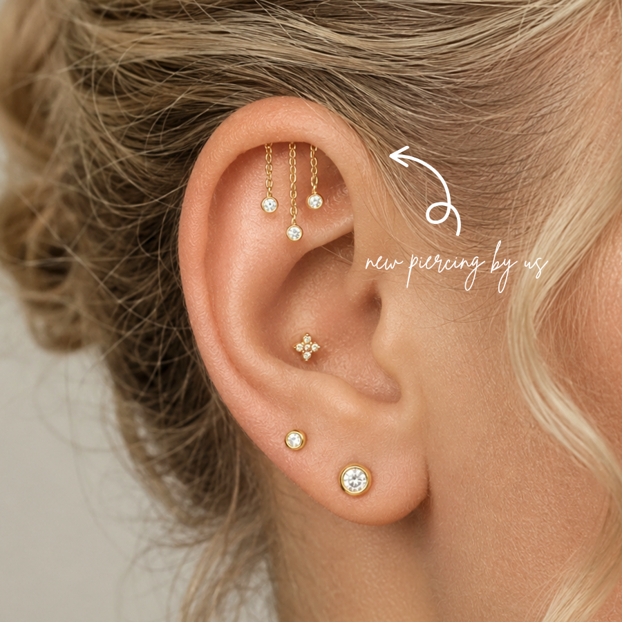 DOVIANA NYC curated ear piercing featuring hidden helix chain dangle earrings, gold CZ bezel studs, and minimalist fine piercing jewelry for everyday ear stacks in New York.